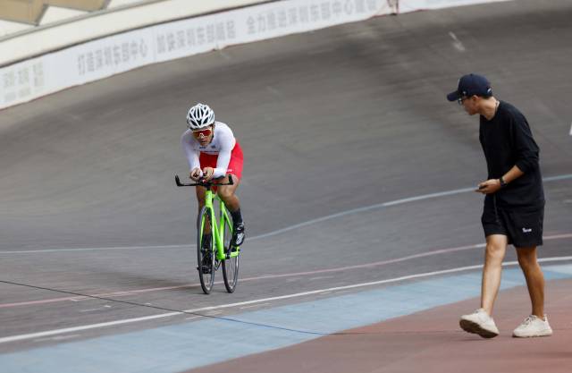 参赛选手在赛场上角逐骑行，教练正在打气助威。
