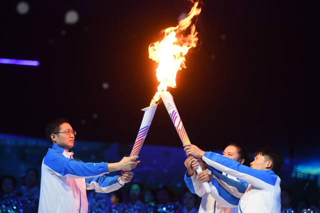 11月5日，火炬手聂双喜（左）与黄雅晴（中）、兰星宇在开幕式上交接。新华社发
